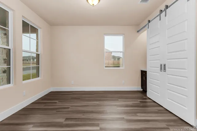 a view of an empty room with wooden floor and a window