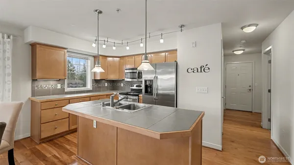 a kitchen with kitchen island a sink appliances and wooden floor