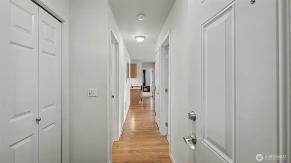 a view of a hallway with wooden floor and a bathroom