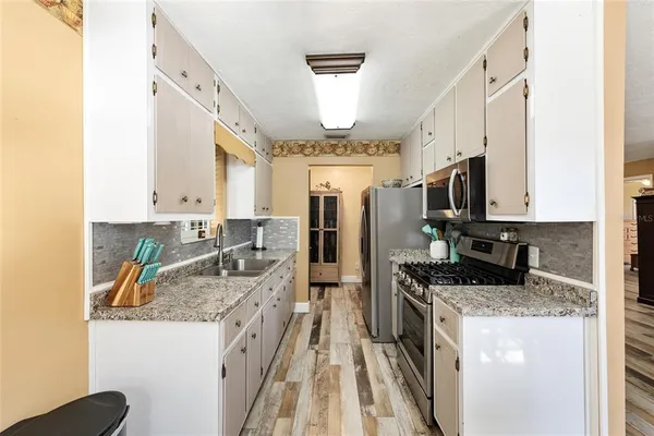 a kitchen with stainless steel appliances granite countertop a refrigerator a stove and a white cabinets