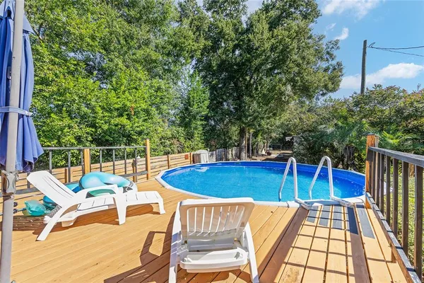 a view of patio with table and chairs under an umbrella with a large tree