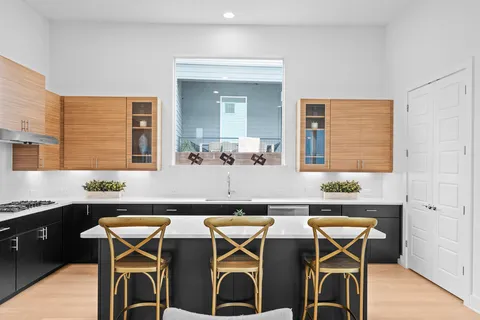 a dining hall with stainless steel appliances kitchen island granite countertop a table chairs in it and wooden floor