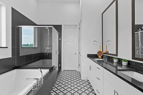 a bathroom with a double vanity sink and mirror with bathtub