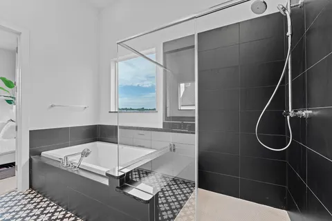 a bathroom with a tub a mirror and a shower