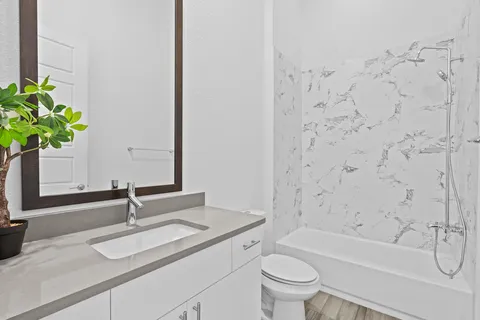 a bathroom with a granite countertop sink a toilet and a bathtub