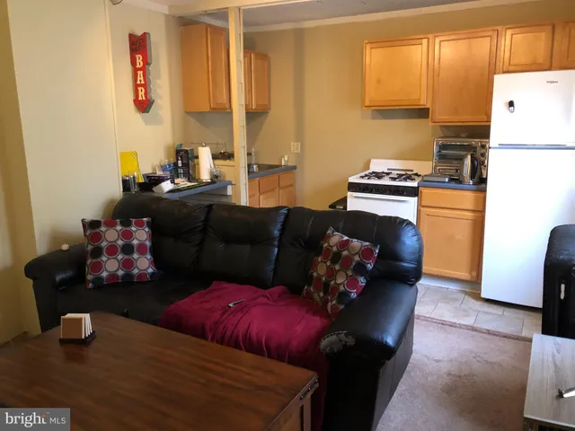 a living room with furniture and a refrigerator