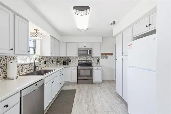a kitchen with white cabinets and white appliances