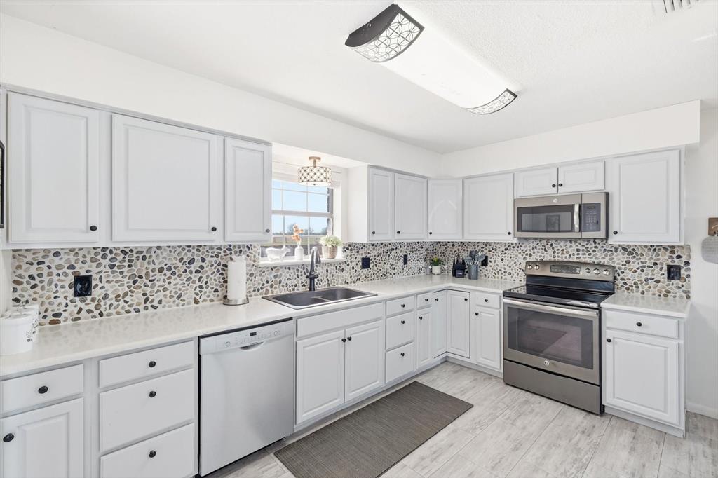 3873 Lois Road East Sanger, TX 76266 - Photo 18 of 40 a kitchen with granite countertop white cabinets and white appliances