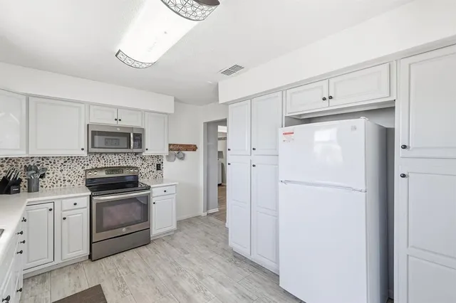 a kitchen with white cabinets and stainless steel appliances