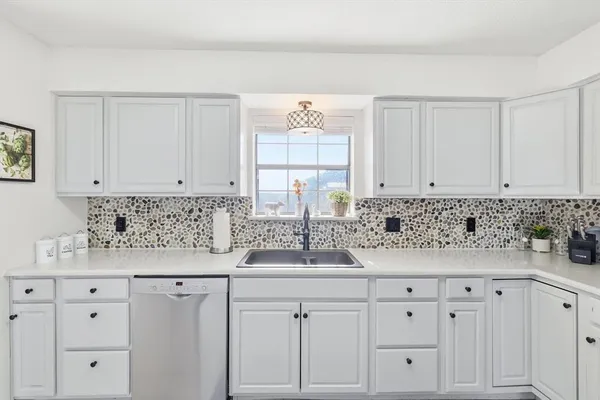 a kitchen with granite countertop white cabinets and a sink