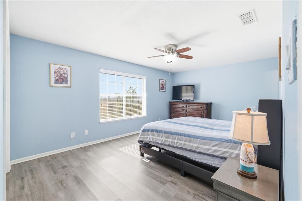 3873 Lois Road East Sanger, TX 76266 - Photo 21 of 40 a spacious bedroom with a bed and a chandelier