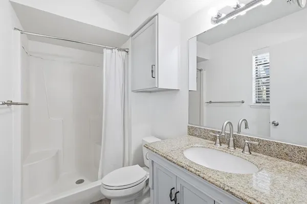a bathroom with a granite countertop sink toilet a mirror and shower