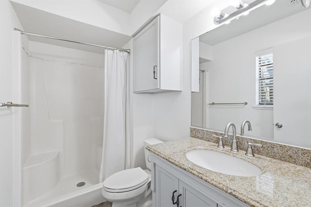 3873 Lois Road East Sanger, TX 76266 - Photo 23 of 40 a bathroom with a granite countertop sink toilet a mirror and shower