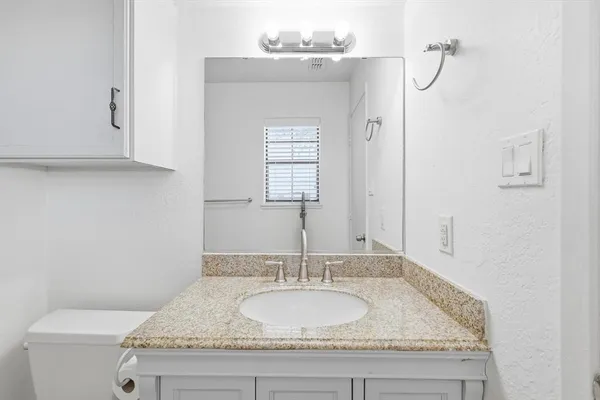 a bathroom with a granite countertop sink and a mirror
