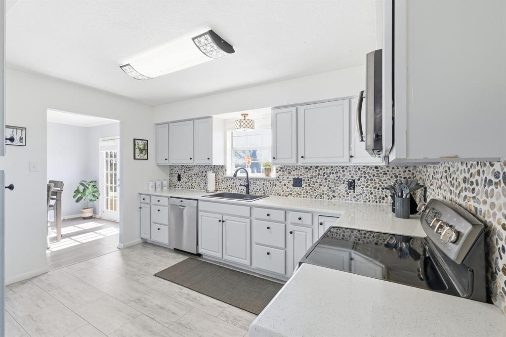 3873 Lois Road East Sanger, TX 76266 - Photo 4 of 40 a kitchen with granite countertop a sink stove and cabinets