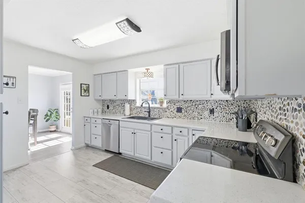 a kitchen with granite countertop a sink stove and cabinets