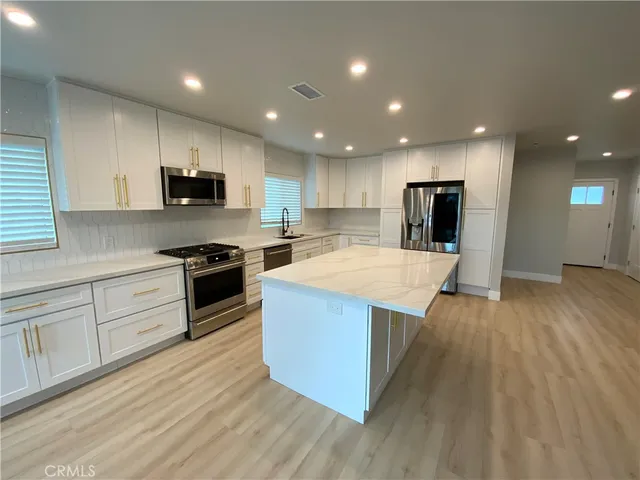 a kitchen with stainless steel appliances kitchen island granite countertop a stove a sink and a refrigerator