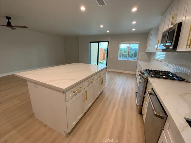 a large white kitchen with wooden floor