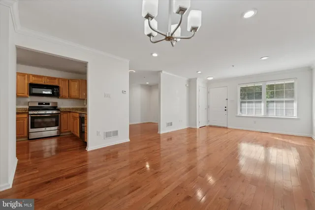 a view of empty room with wooden floor and kitchen view