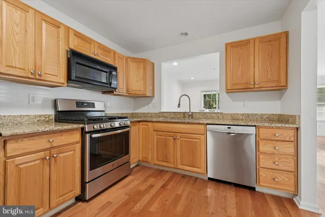 a kitchen with granite countertop cabinets stainless steel appliances and wooden floor