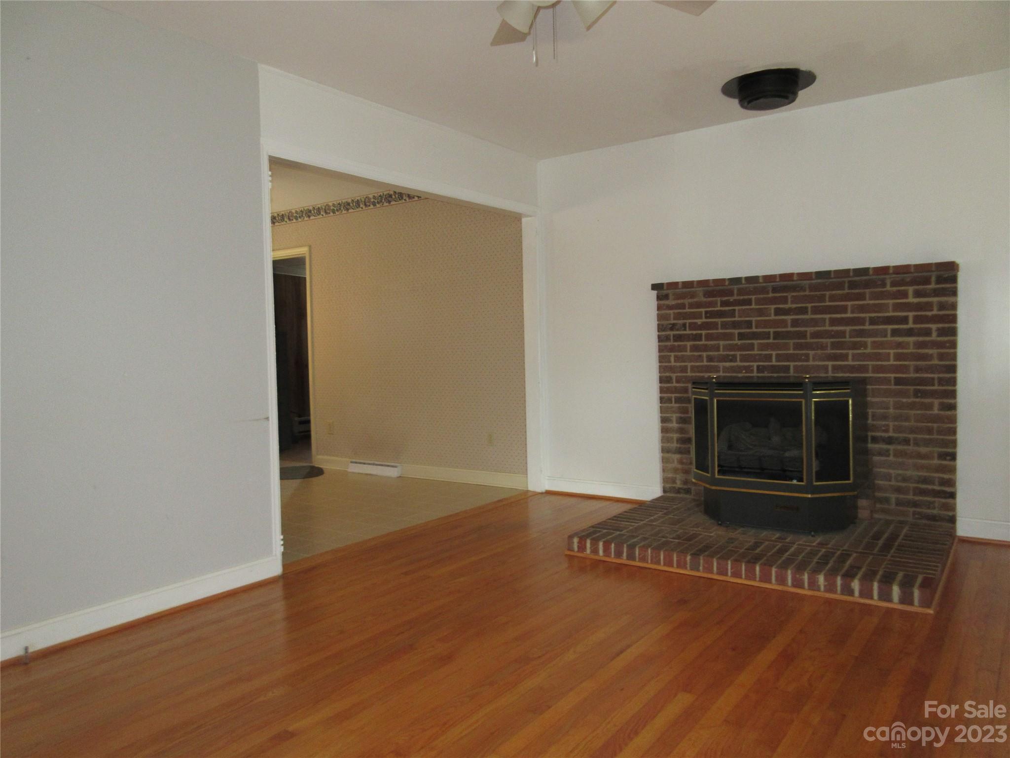 145 Hodge Street Rutherfordton, NC 28139 - Photo 9 of 24 a view of an empty room with wooden floor and a fireplace