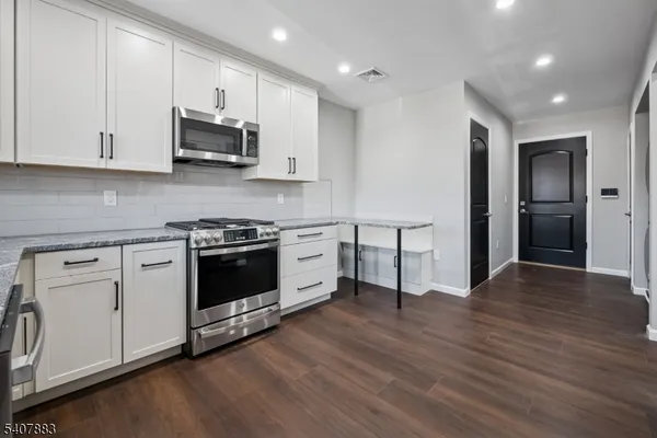 a kitchen with stainless steel appliances white cabinets and wooden floors