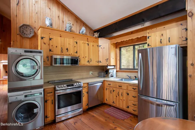 a kitchen with stainless steel appliances granite countertop a refrigerator a stove and a wooden floor