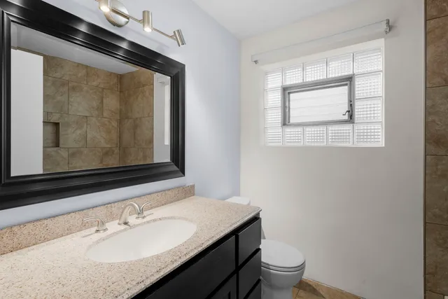 a bathroom with a granite countertop sink toilet and mirror