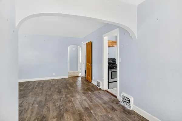a view of an empty room with wooden floor and closet