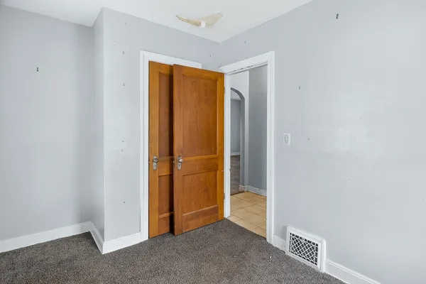 an empty room with wooden floor closet and windows