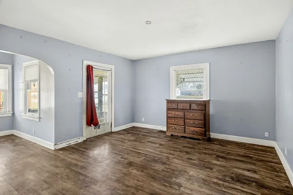 a view of an empty room with window and wooden floor