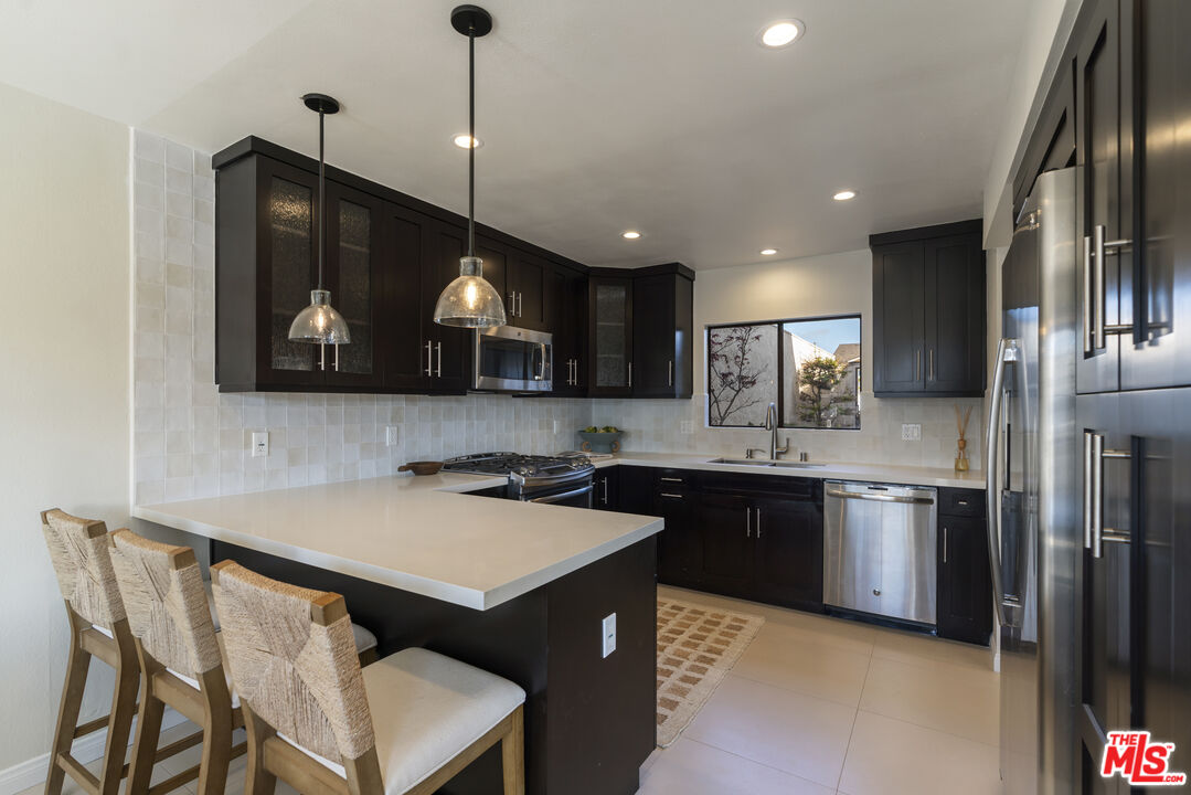 4555 Falkirk Bay, Unit BAY Oxnard, CA 93035 - Photo 13 of 46 a kitchen with stainless steel appliances granite countertop a sink a stove a refrigerator a microwave oven with cabinets and wooden floor
