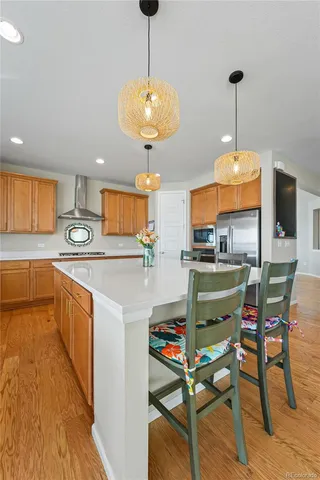 a kitchen with stainless steel appliances granite countertop a stove a sink a microwave a dining table and chairs with wooden floor