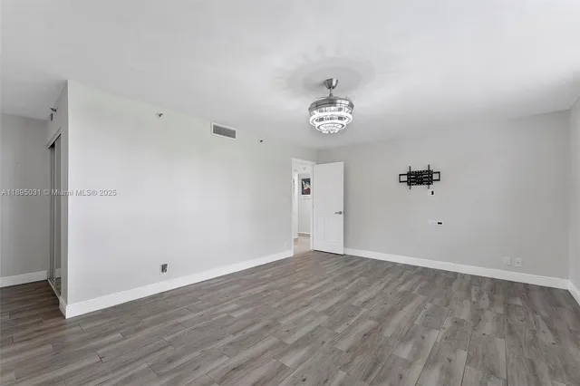 an empty room with wooden floor and ceiling fan