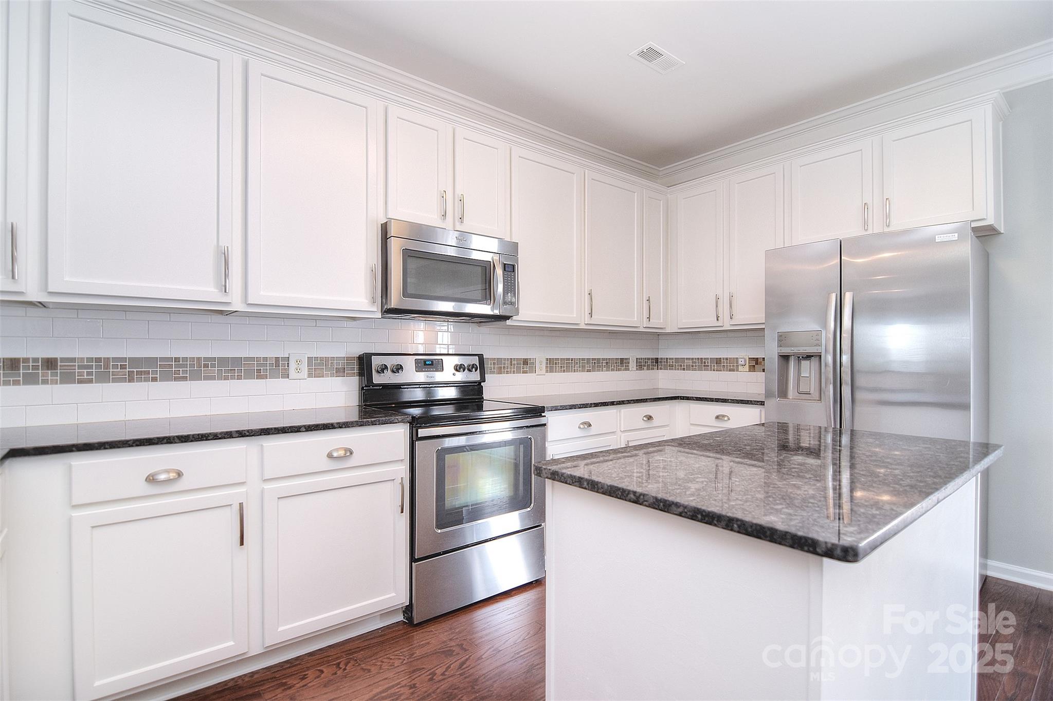 7002 Creft Circle Indian Trail, NC 28079 - Photo 11 of 47 a kitchen with kitchen island granite countertop a sink stainless steel appliances and white cabinets
