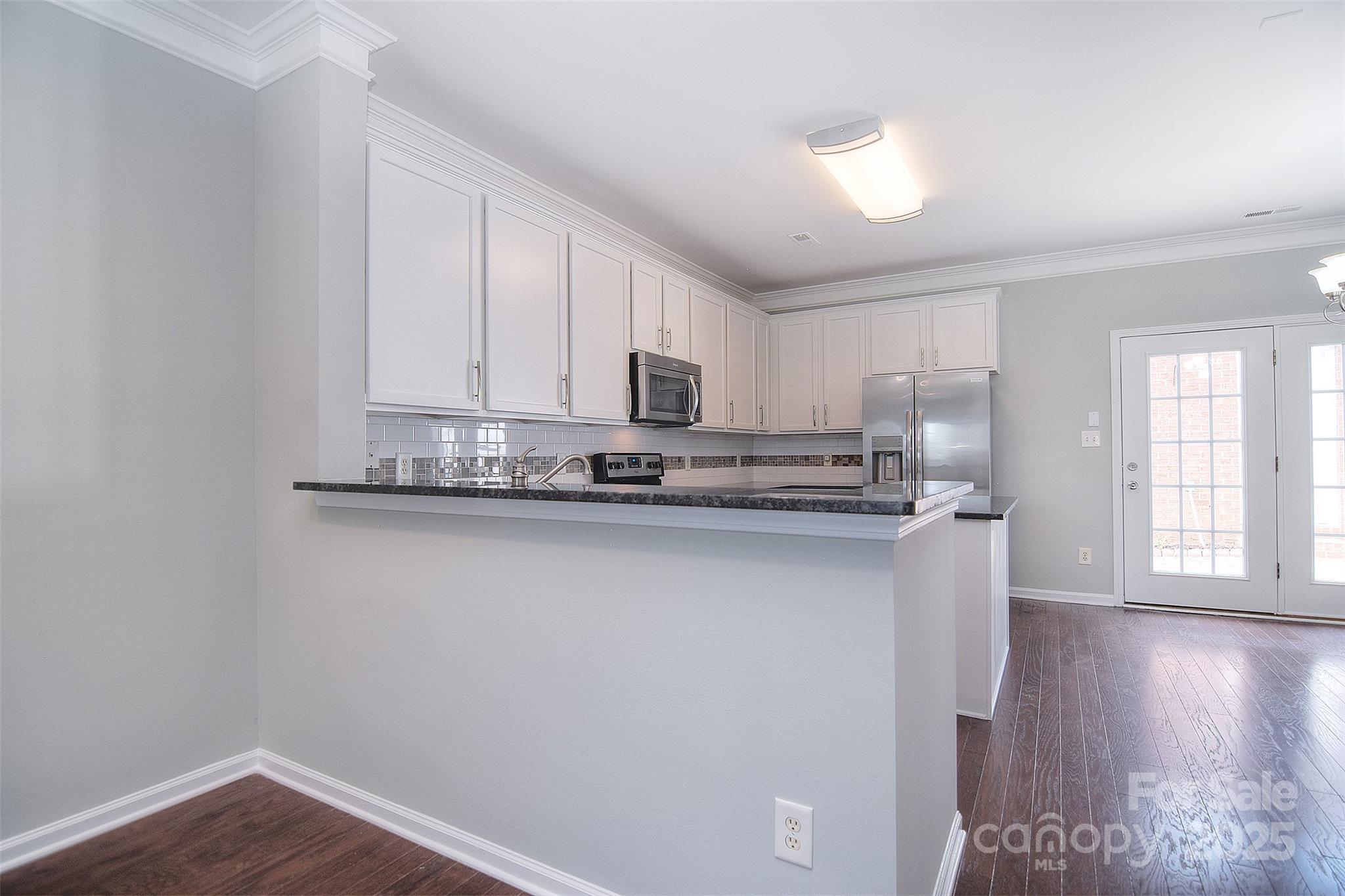 7002 Creft Circle Indian Trail, NC 28079 - Photo 10 of 47 a kitchen with stainless steel appliances granite countertop a refrigerator a stove a sink and a microwave oven with wooden floor