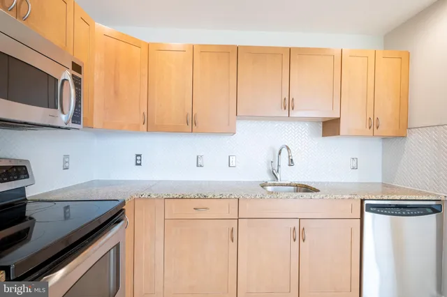 a kitchen with stainless steel appliances granite countertop a sink a stove and white cabinets