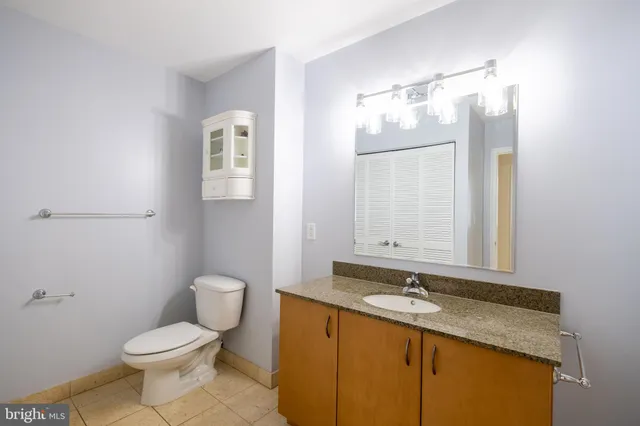 a bathroom with a granite countertop sink toilet and mirror