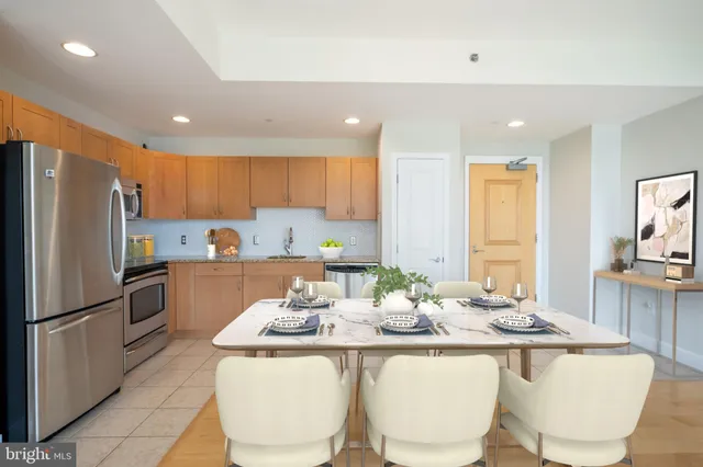 a kitchen with stainless steel appliances granite countertop a sink a stove a refrigerator a kitchen island and chairs