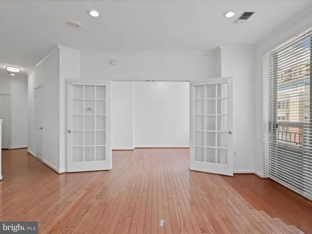 an empty room with wooden floor and windows with curtains
