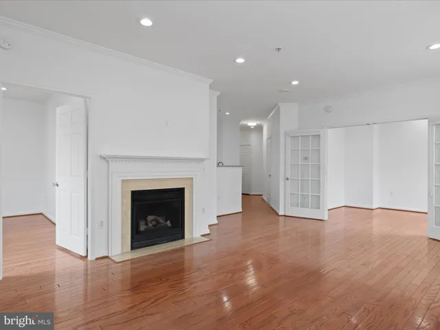 a view of an empty room with wooden floor fireplace and a window