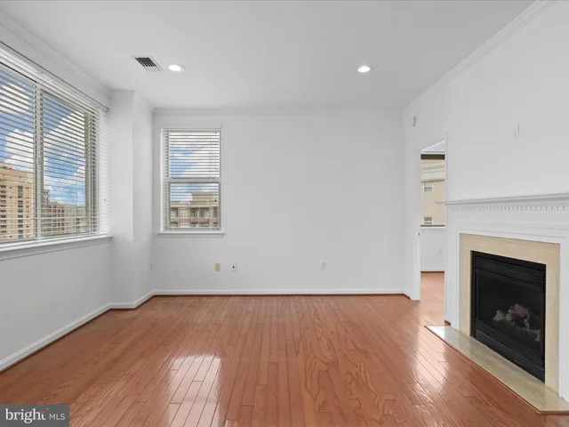 an empty room with wooden floor fireplace and windows