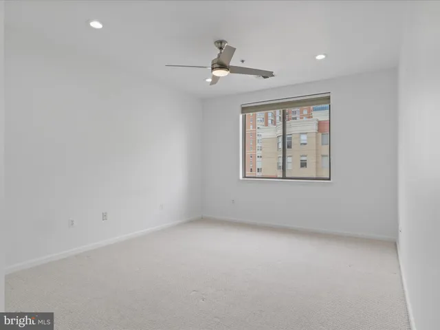 an empty room with windows and ceiling fan