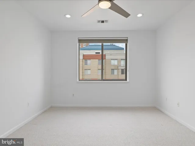 an empty room with a window and ceiling fan