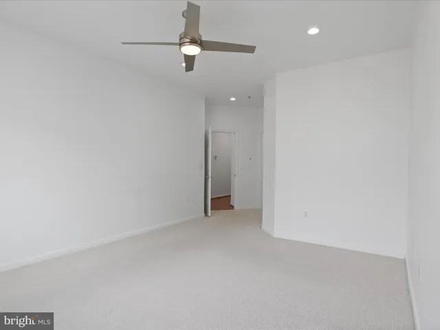 an empty room with a ceiling fan and carpet