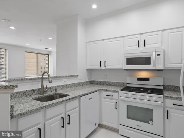 a kitchen with stainless steel appliances granite countertop white cabinets a sink and a stove