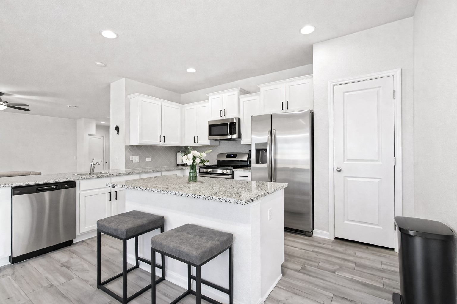 940 Paddock Lane Georgetown, TX 78626 - Photo 16 of 32 Kitchen featuring white cabinetry, stainless steel appliances, speckled countertops, and wood-finish flooring