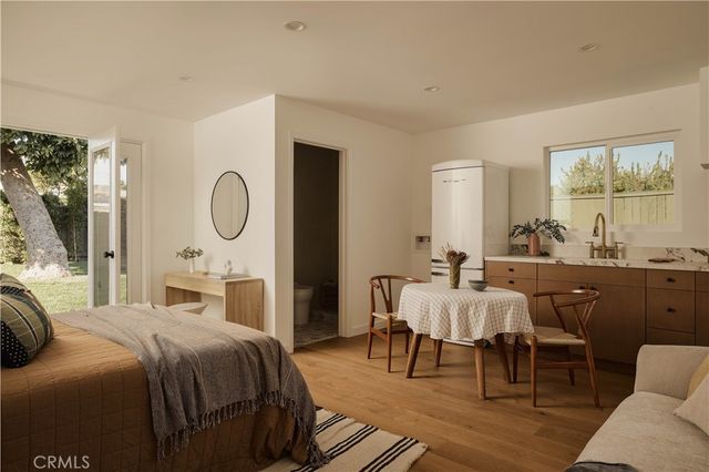a bedroom with a bed a mirror and a large window with balcony view