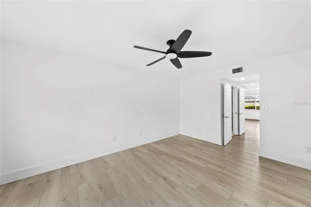 an empty room with wooden floor and a ceiling fan