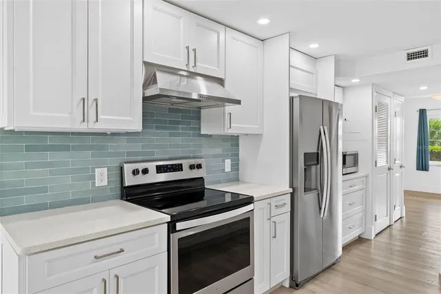 a kitchen with stainless steel appliances white cabinets and a refrigerator